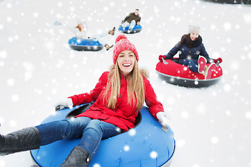 Image showing group of happy friends sliding down on snow tubes