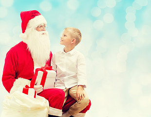 Image showing smiling little boy with santa claus and gifts