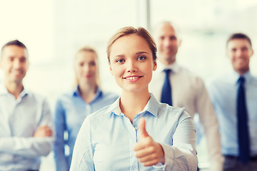 Image showing smiling businesswoman showing thumbs up in office