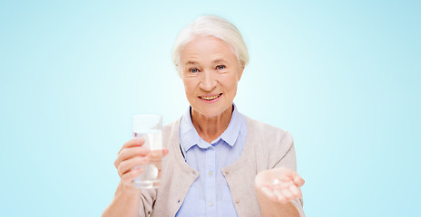 Image showing happy senior woman with water and medicine
