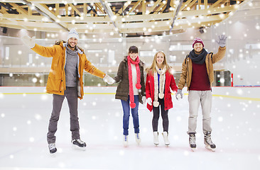 Image showing happy friends waving hands on skating rink