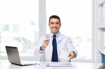 Image showing smiling doctor with tablets and laptop in office