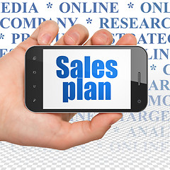 Image showing Marketing concept: Hand Holding Smartphone with Sales Plan on display