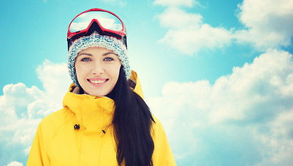 Image showing happy young woman in ski goggles over blue sky