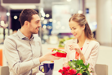 Image showing happy couple with present and flowers in mall