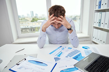 Image showing stressed businessman with papers in office