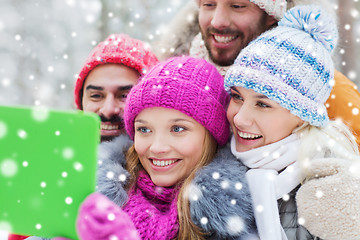 Image showing smiling friends with tablet pc in winter forest
