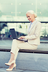 Image showing smiling businesswoman working with laptop outdoors