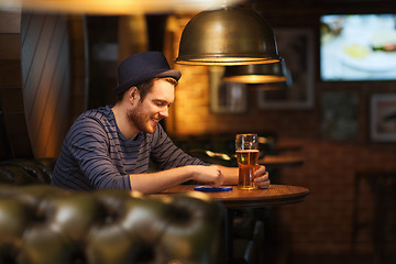 Image showing man with smartphone and beer texting at bar