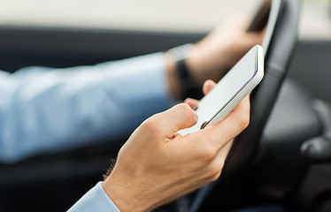 Image showing close up of man hand with smartphone driving car