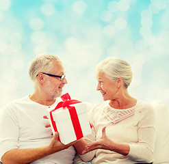 Image showing happy senior couple with gift box at home