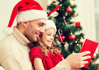 Image showing smiling father and daughter reading book