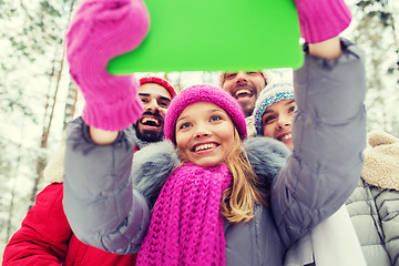 Image showing smiling friends with tablet pc in winter forest