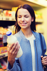 Image showing happy woman holding milk bottle in market