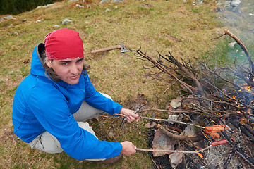 Image showing hiking man prepare tasty sausages on campfire