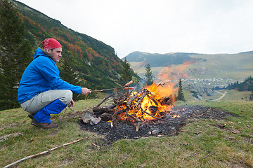 Image showing hiking man prepare tasty sausages on campfire