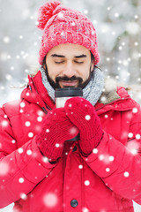 Image showing smiling young man with cup in winter forest