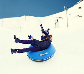 Image showing happy young man sliding down on snow tube