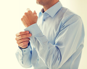 Image showing close up of man fastening buttons on shirt sleeve