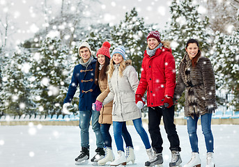 Image showing happy friends ice skating on rink outdoors