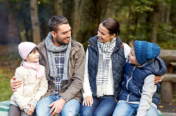 Image showing happy family sitting on bench and talking at camp