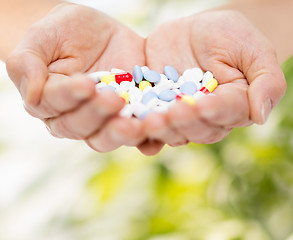 Image showing close up of senior woman hands with pills