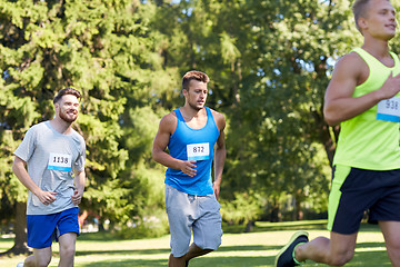 Image showing happy young sportsmen racing wit badge numbers