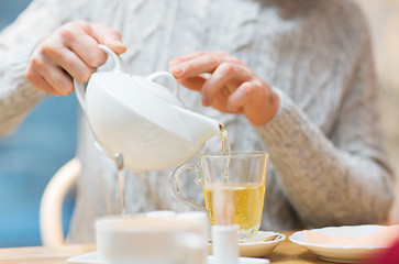 Image showing close up of man with pot pouring tea at cafe