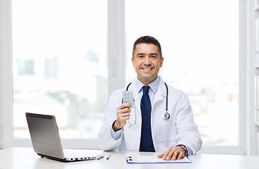 Image showing smiling doctor with tablets and laptop in office