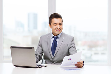 Image showing smiling businessman with laptop and papers