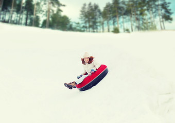 Image showing happy teenage girl sliding down on snow tube