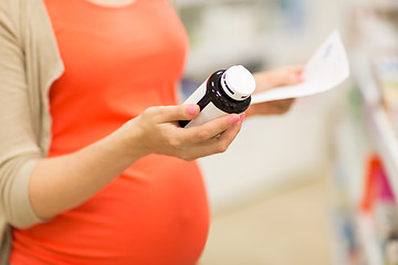Image showing pregnant woman with medication jar at pharmacy