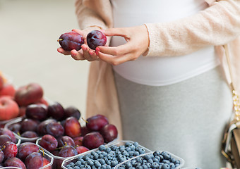 Image showing pregnant woman choosing plums at street market