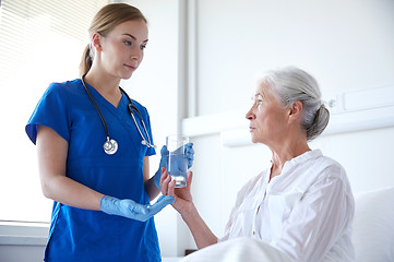 Image showing nurse giving medicine to senior woman at hospital