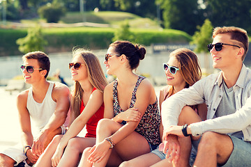 Image showing group of smiling friends sitting on city square