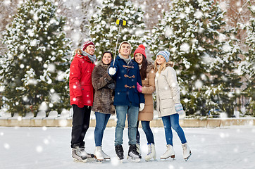 Image showing happy friends with smartphone on ice skating rink