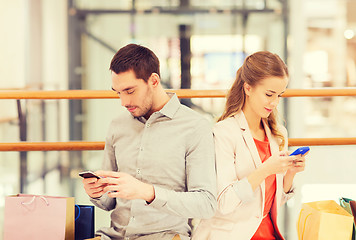 Image showing couple with smartphones and shopping bags in mall