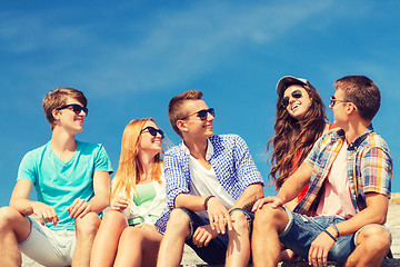 Image showing group of smiling friends sitting on city street