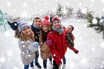 Image showing happy friends with smartphone on ice skating rink