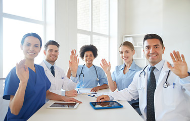 Image showing happy doctors meeting and waving hands at hospital