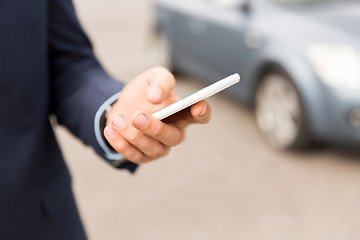 Image showing close up of man hand with smartphone and car