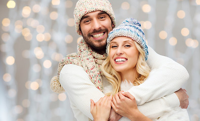 Image showing happy couple in winter clothes hugging over lights