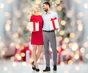 Image showing happy couple with gift boxes over christmas lights