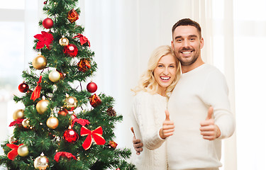 Image showing happy couple showing thumbs up with christmas tree