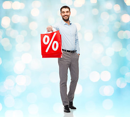 Image showing smiling man with red shopping bag over blue lights