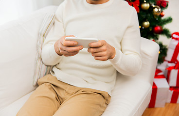 Image showing smiling man with smartphone at home for christmas