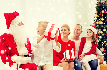 Image showing smiling family with santa claus and gifts at home