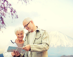 Image showing happy senior couple with travel map over mountains