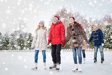 Image showing happy friends ice skating on rink outdoors