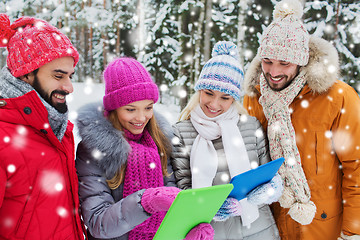 Image showing smiling friends with tablet pc in winter forest